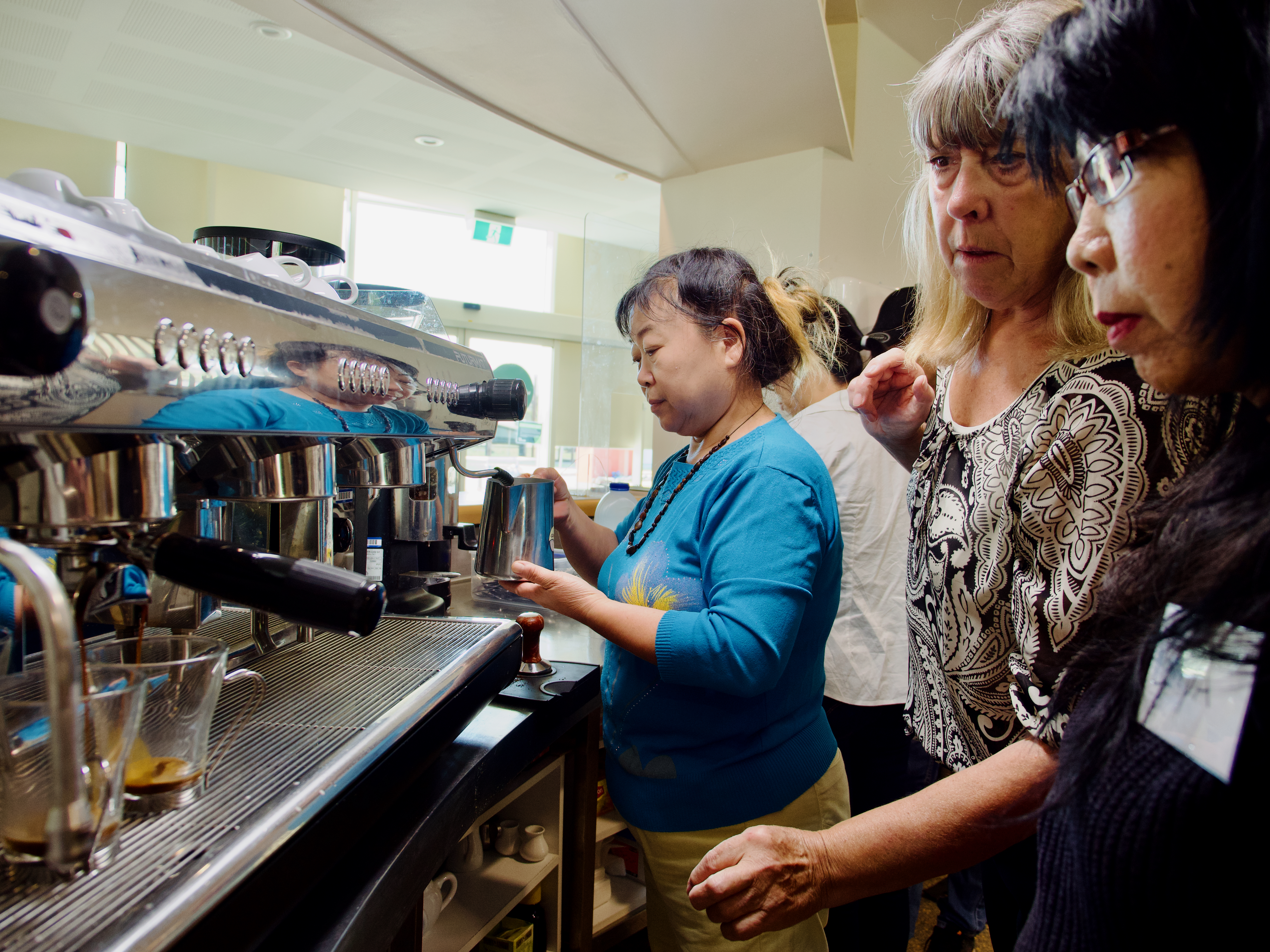 A woman learning how to make coffees.